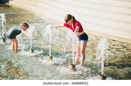 Two Happy Kids Playing In Public City Fountain On A Very Hot Day