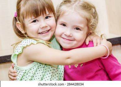 Two happy little girls hugging in the room - Shutterstock ID 284428034