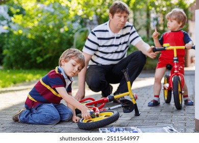 Two happy little kid boys and father repair chain on bikes and change wheel of balance bicycle - Powered by Shutterstock