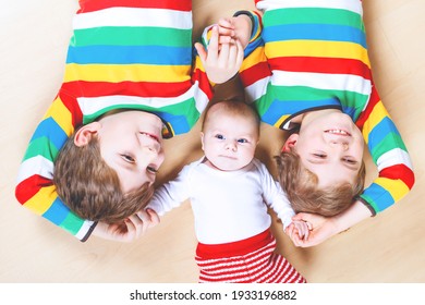 Two happy little preschool kids boys with newborn baby girl, cute sister. Siblings, twins children and baby playing together. Kids bonding. Family of three, love. kids in colorful fashion clothes.