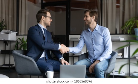 Two Happy Male Business Partners Handshaking Reaching Agreement On Negotiations, Smiling Leader Greeting Skilled Capable Worker Employee With Reward Promotion, Content Client And Banker Finishing Deal