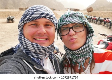 Two happy married couple bikers near atvs quad bike in sand desert nature. All terrain vehicle in desert on rocky mountains background. Off road driving on desert road - Powered by Shutterstock