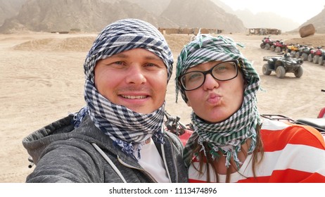 Two happy married couple bikers near atvs quad bike in sand desert nature. All terrain vehicle in desert on rocky mountains background. Off road driving on desert road - Powered by Shutterstock