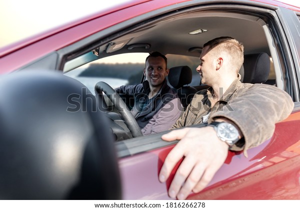 two happy men friends in the car on the\
background of a beautiful\
landscape