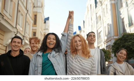 Two happy mixed race women lift hands up together in a mass protest against racism. - Powered by Shutterstock