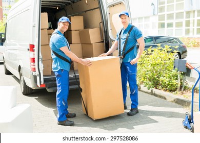 Two Happy Movers In Blue Uniform Loading Boxes In Truck