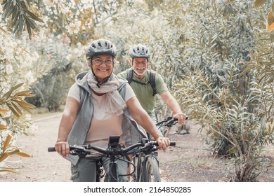 Two Happy Old Mature People Enjoying And Riding Bikes Together To Be Fit And Healthy Outdoors. Active Seniors Having Fun Training In Nature.