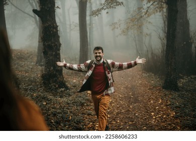 Two happy people are about to hug during outdoor activity. Focus on a man walking towards the woman with spread hands. - Shutterstock ID 2258606233
