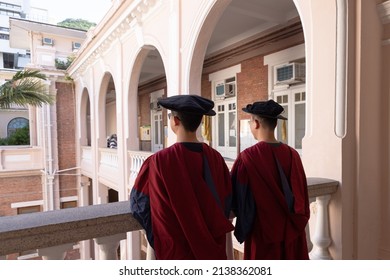 Two Happy Proud PhD Graduated Male Students In Academic Dress Gown In Old Campus Building In Hong Kong. Back View