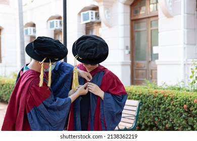 Two Happy Proud PhD Graduated Male Students Help Each Other To Put On Academic Dress Or Gown In Old Campus Building In Hong Kong