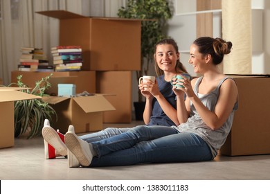 Two Happy Roommates Moving Home Resting And Talking Sitting On The Floor In The Night