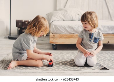 two happy siblings playing with toy cars at home in the morning. Casual lifestyle in bedroom
