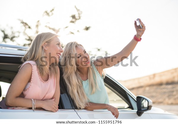Two happy sister in car happy and smiling after\
shopping taking selfie