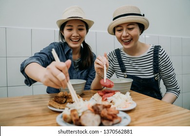 Two Happy Smiling Asian Girls Travelers Love Delicious Food Trying Taiwanese Local Meal Sitting In Vendor Traditional Restaurant Shop Store. Young Women Cheerful Using Chopsticks Ready To Eat.