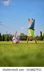 Two Happy Smiling Children Tumbling On Green Grass. Cheerful Brother And Sister Laugh Together. Happy Kids Have Fun On The Park Lawn. Children's Day