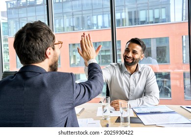 Two happy smiling diverse professional businessmen executive leaders giving highfive after successful financial business deal acquisition merger at board office meeting. Partnership high five concept.