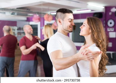 Two happy smiling loving couples having dancing class in club
