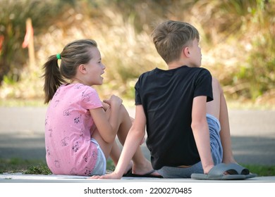 Two happy smiling teenage children, boy and girl sitting outdoors resting, having fun on summer sunny day - Shutterstock ID 2200270485