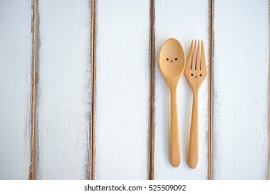 Two happy spoon and fork on wood texture of dining table. Concept about happiness and friendship.