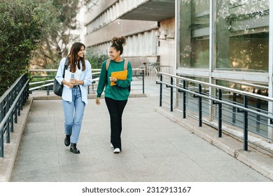 Two happy students girls walking and talking each other in University campus after classes - Shutterstock ID 2312913167