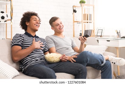 Two Happy Teen Guys Watching Comedy Movie On Tv And Eating Popcorn At Home, Copy Space