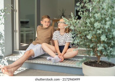 Two Happy Teenage Siblings Having Fun Together Sitting On Porch Of Terrace