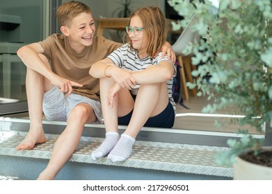 Two Happy Teenage Siblings Having Fun Together Sitting On Porch Of Terrace