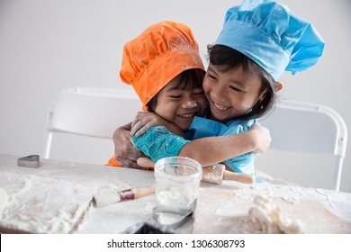two happy toddler embracing each other while make cookies together wearing apron