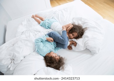 Two happy twin brothers romping around in bed - Powered by Shutterstock