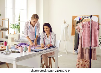 Two happy woman business partners work with fabrics textiles at fashion atelier. Smiling female seamstress dressmakers create garment clothing pieces at workshop. Style, design, entrepreneurship. - Powered by Shutterstock