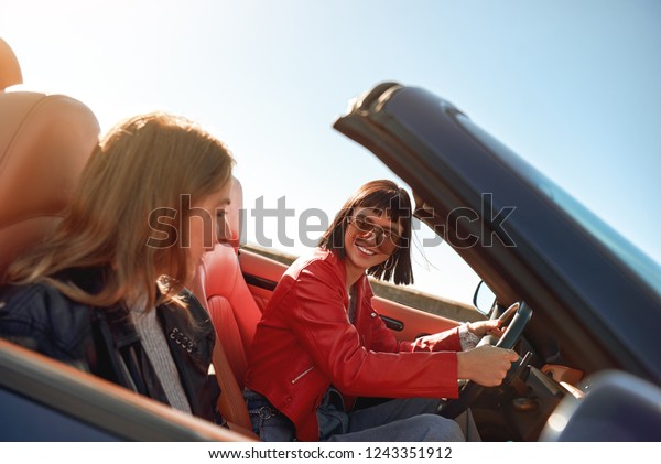 Two\
happy women in the cabriolet driving and having\
fun