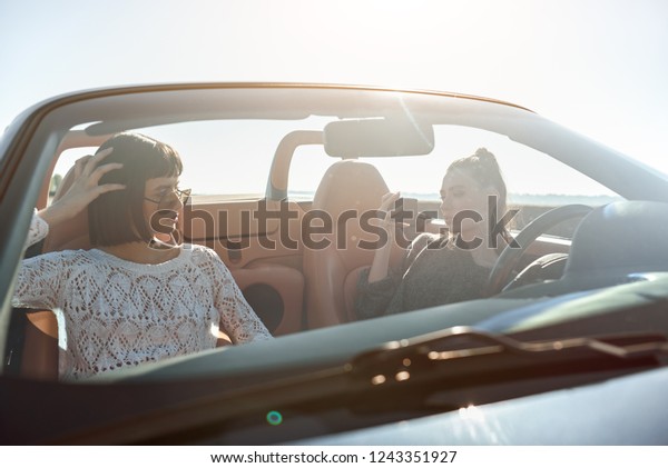 Two\
happy women in the cabriolet photographing each\
other