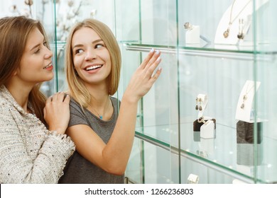 Two happy women choosing new necklace and discussing choice in shop. Female customers standing together near showcase, looking at each other and talking. Concept of choice and happiness. - Powered by Shutterstock