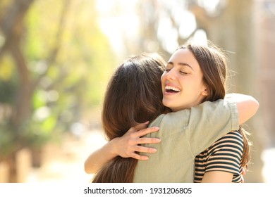 Two happy women embracing after meeting in the street a sunny day