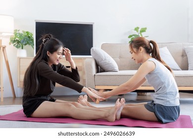 Two Happy Women Enjoying Yoga Together at Home. Lesbian Couple Bonding and Exercising on a Yoga Mat in a Cozy Living Room - Powered by Shutterstock