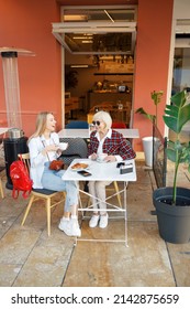 Two Happy Women Having Coffee In Cafe