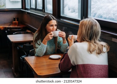 Two happy women having leisure drink tea and chat in a cafe.