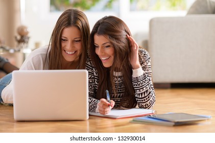 Two Happy Women Looking At Laptop While Lying On Floor