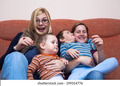 Two happy women playing with children at home