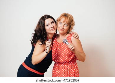 Two happy women singing to microphones and having fun - Shutterstock ID 471932069