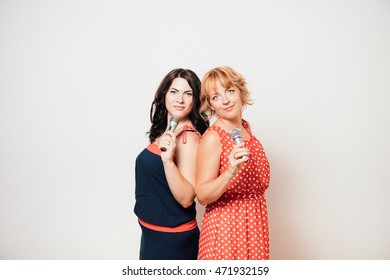 Two happy women singing to microphones and having fun - Shutterstock ID 471932159