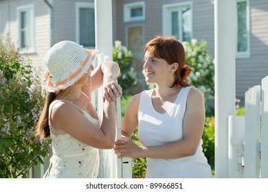 Two Happy Women Talking Near Fence Wicket