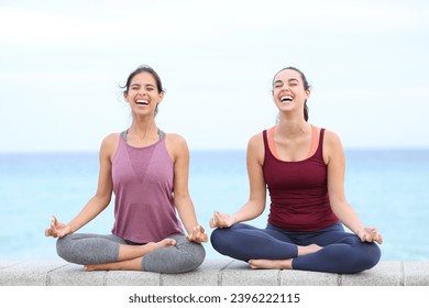 Two happy yogis laughing doing yoga on the beach