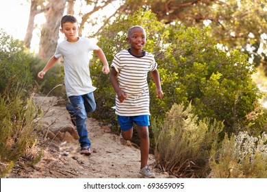 Two Happy Young Boys Running Down A Forest Path