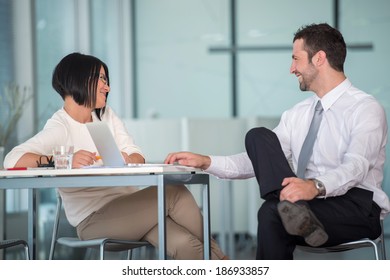 Two Happy Young Coworkers Talking In Office