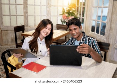 Two happy young diversity businesspeople having a video call in a cafe. Two Indonesian cheerful entrepreneur working together and entering online meeting.  - Powered by Shutterstock