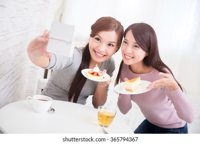 Two Happy Young Female Friends Take Selfie Picture By Smart Phone, With Coffee Cups And Cakes In The Living Room At Home, Healthy Lifestyle Concept, Asian Beauty