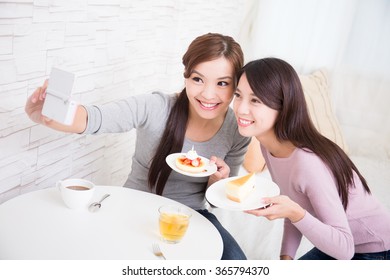 Two Happy Young Female Friends Take Selfie Picture By Smart Phone, With Coffee Cups And Cakes In The Living Room At Home, Healthy Lifestyle Concept, Asian Beauty