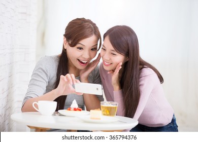 Two Happy Young Female Friends Take Selfie Picture By Smart Phone, With Coffee Cups And Cakes In The Living Room At Home, Healthy Lifestyle Concept, Asian Beauty