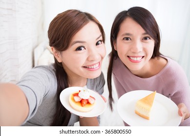 Two Happy Young Female Friends Take Selfie Picture With Coffee Cups And Cakes In The Living Room At Home, Asian Beauty